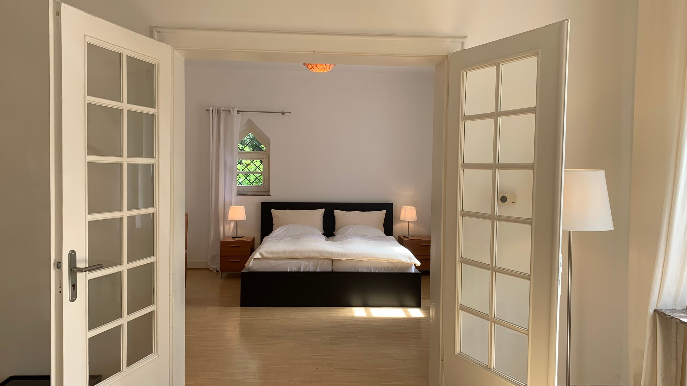Blick durch die Flügeltüren in das Schlafzimmer des Apartment Linde